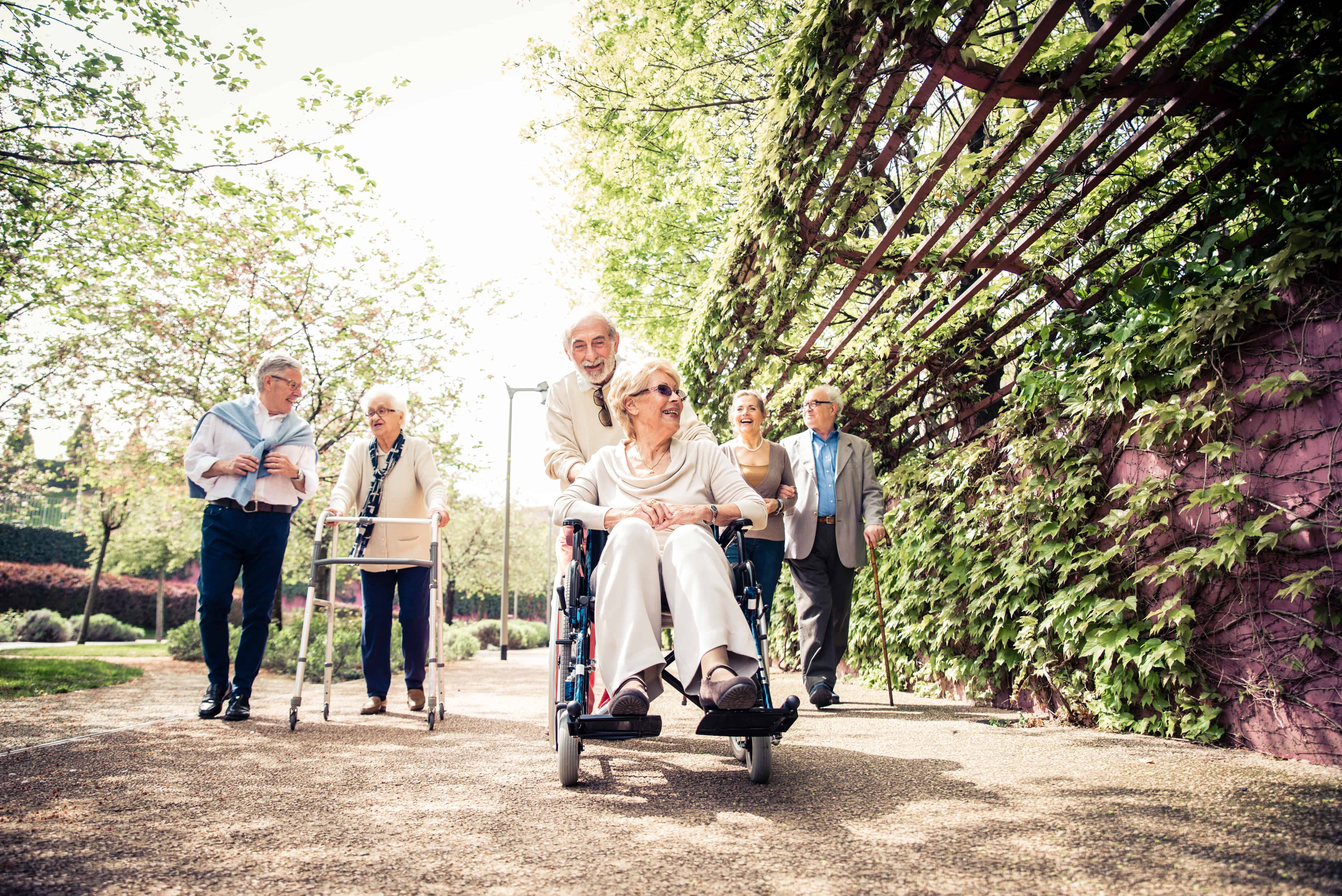 Group of senior people with some diseases walking outdoors - Mature group of friends spending time together