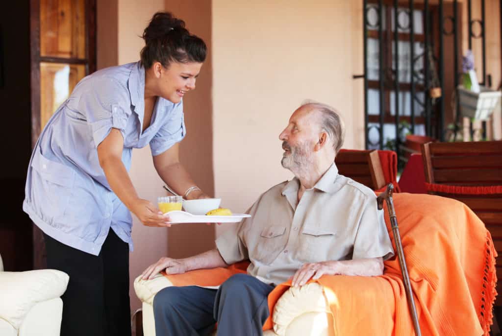 elderly senior being brought meal by a nurse