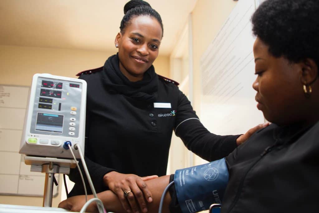 a black nurse takes the blood pressure of a black patient