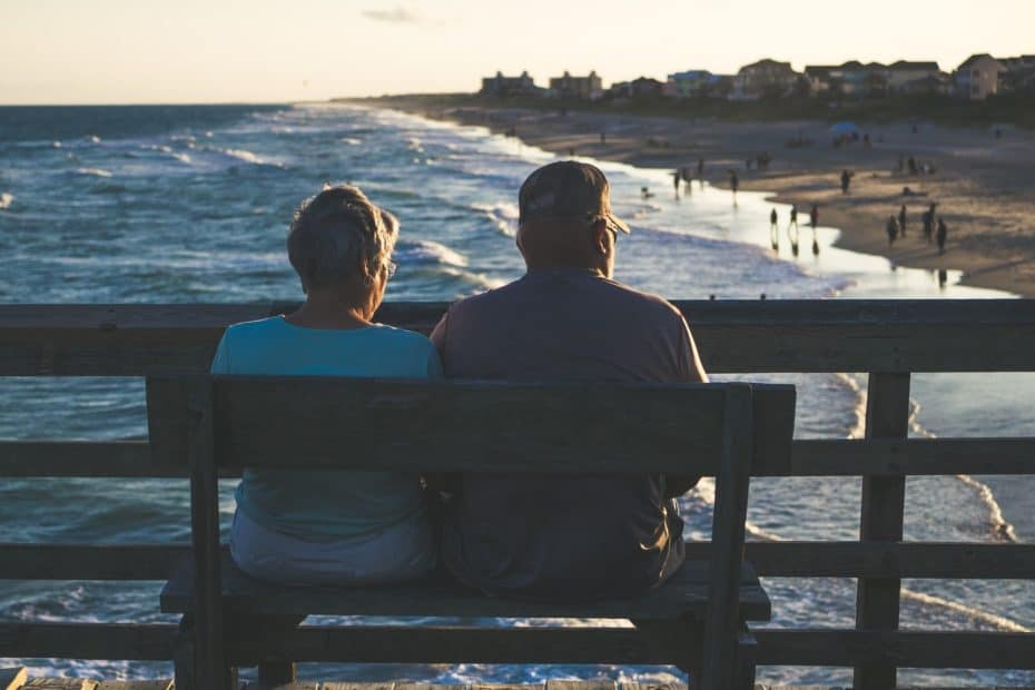 Elderly couple sitting by ocean