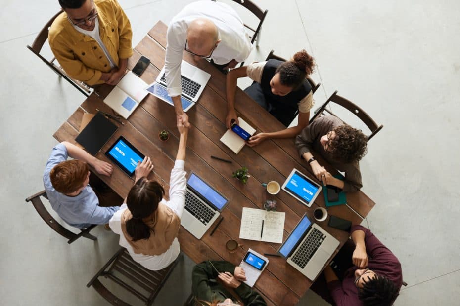 a picture of a group of diverse business men and women sitting around a table. Two are shaking hands. Equity Measures