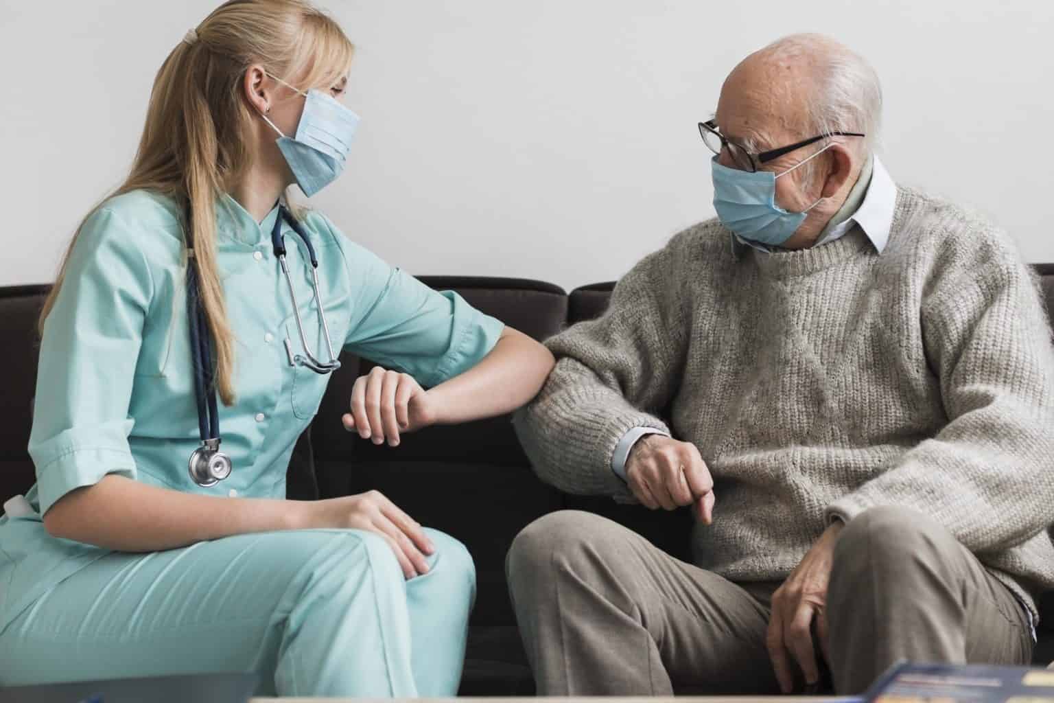 photograph of a nurse and an older man touching elbows