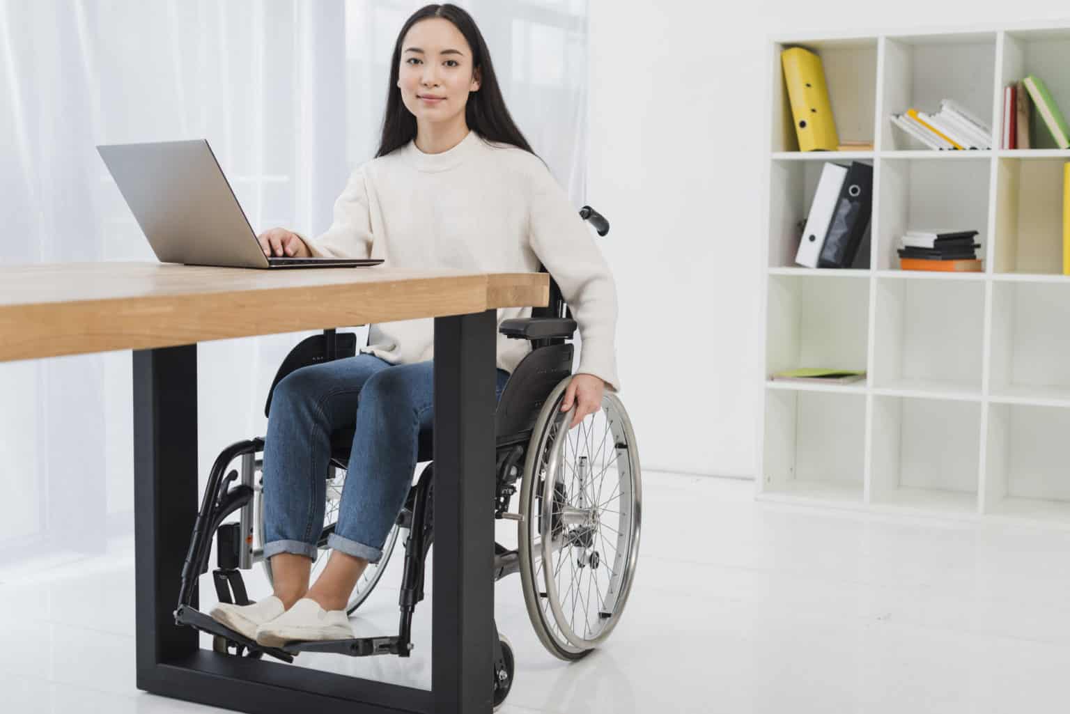 portrait-confident-young-businesswoman-sitting-wheelchair-using-laptop-office