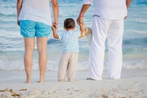 child on the beach holding his parents hands