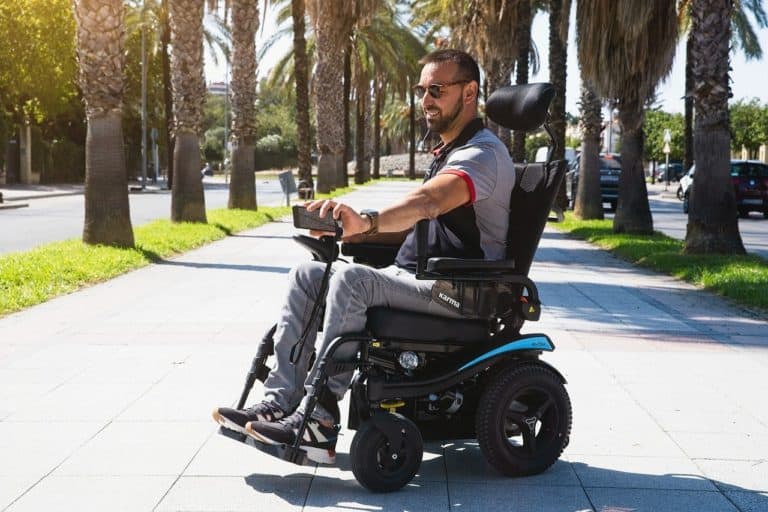 man in a motorized wheelchair moving down a sidewalk