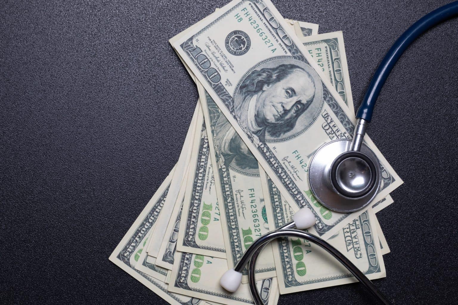 Stethoscope on dollar banknotes, healthcare payment concept