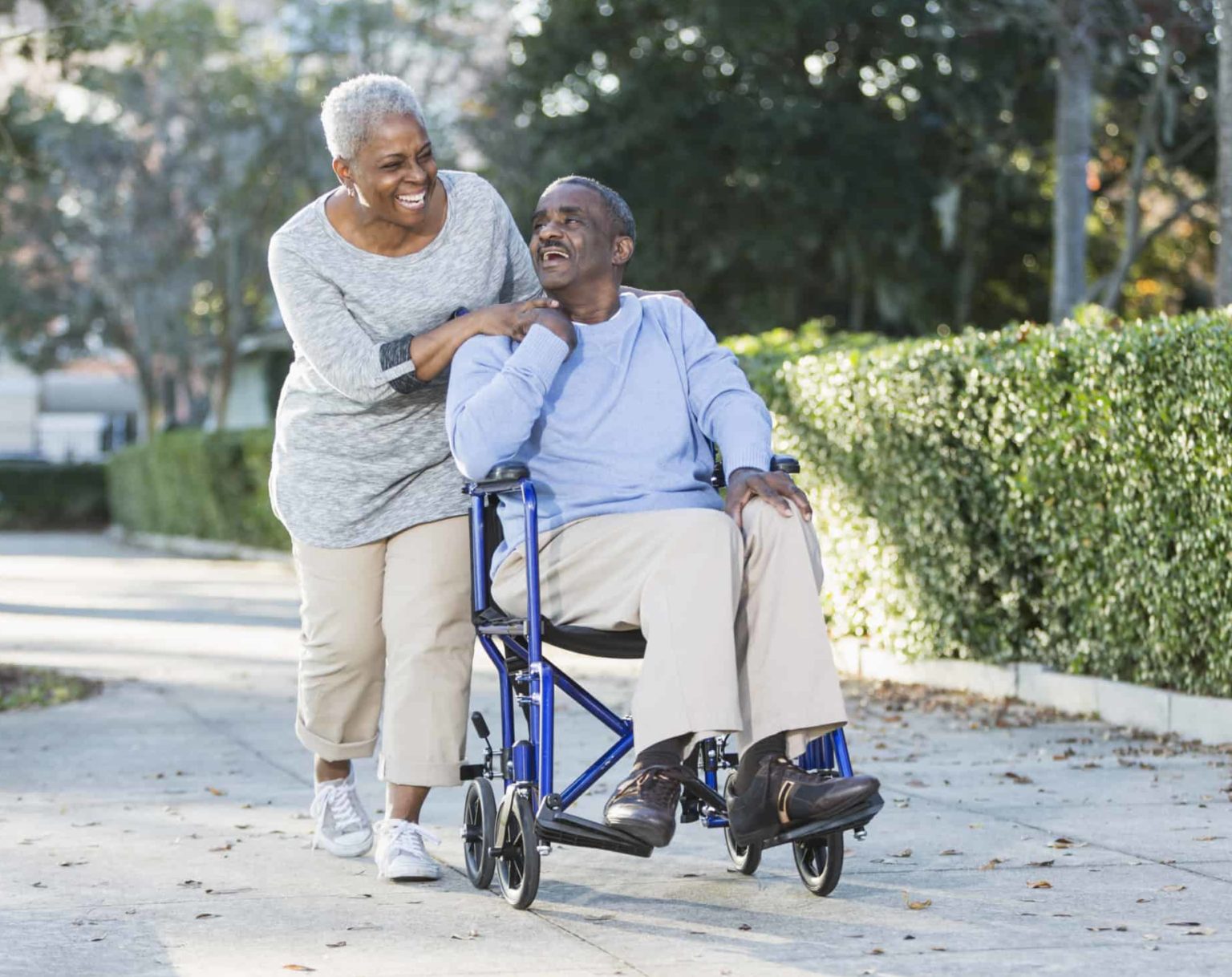 Senior woman pushing her husband in a wheelchair