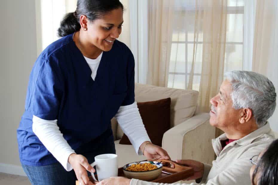 elderly man being waited on by a care giver