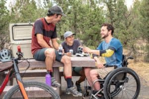 man in a wheelchair in the woods with friends