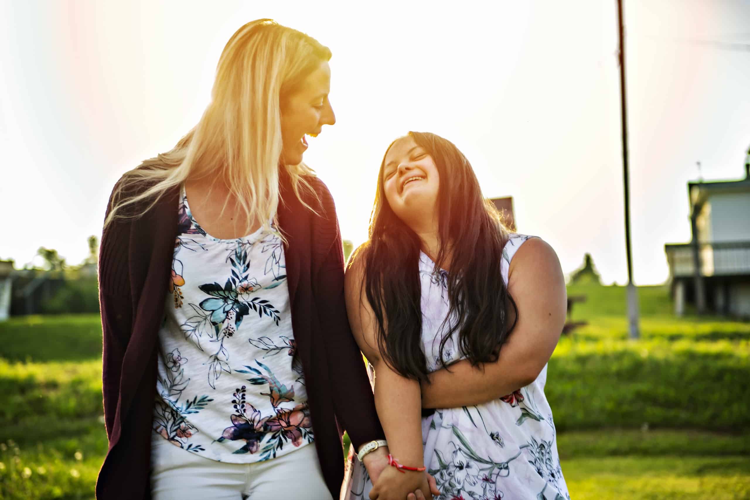 Portrait of trisomie 21 adult girl smilin outside at sunset with family friend