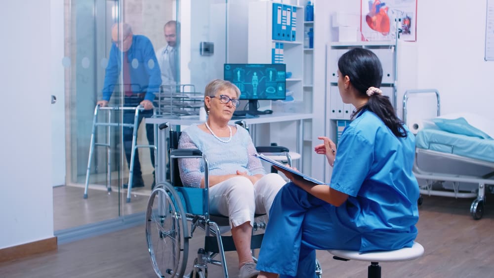 nurse-talking-with-senior-woman-with-walking-disabilities-sitting-wheelchair-into-private-modern-recovery-clinic-hospital-handicapped-old-retired-patient-medical-consultation-advice